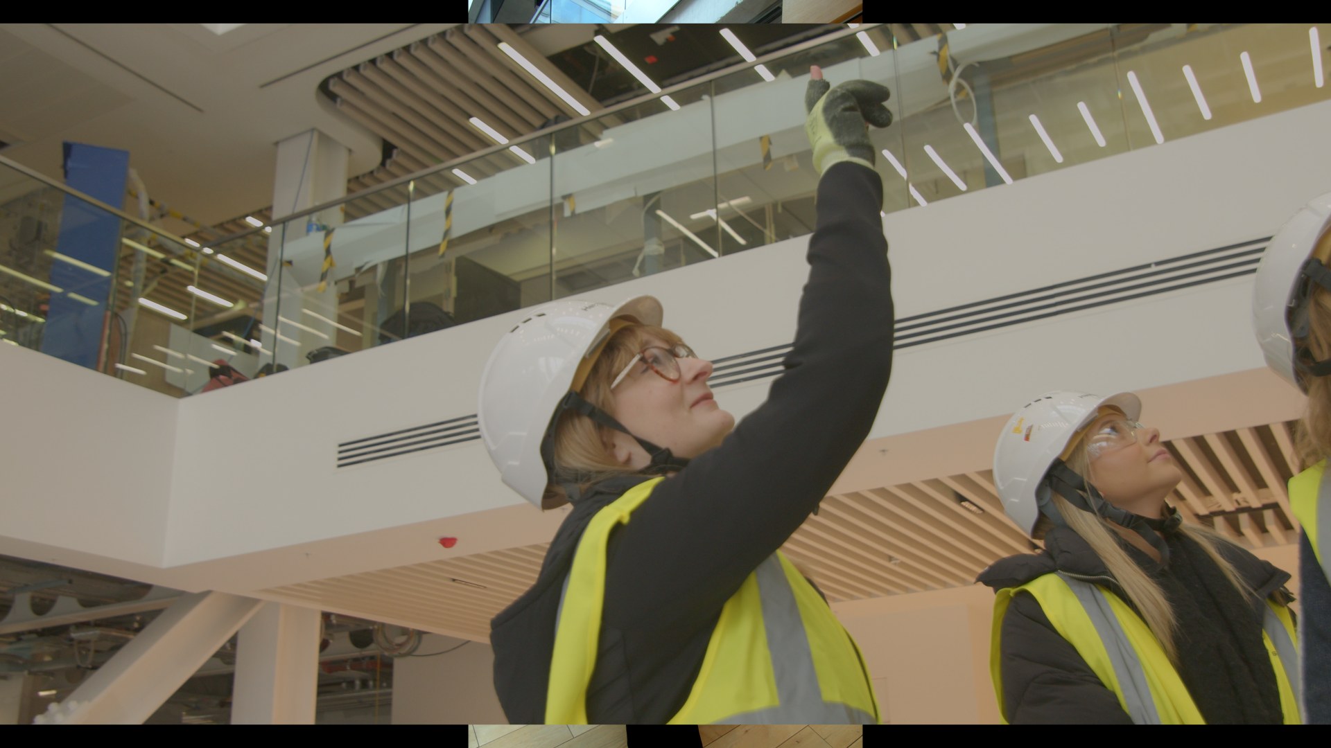An architect in a hard hat reaching up to the underside of a new ceiling.