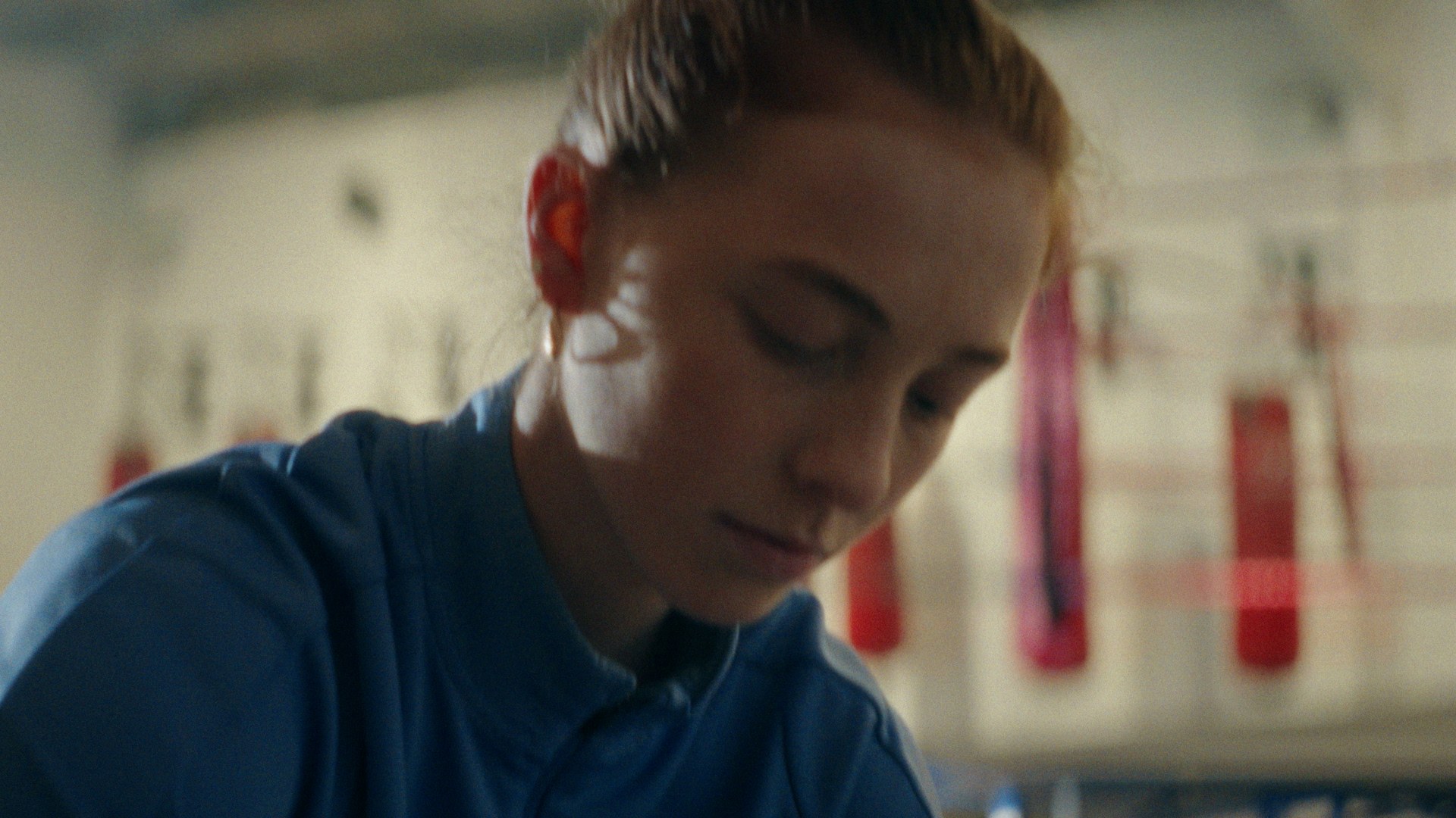 The boxer between rounds, head down, the bags behind her.
