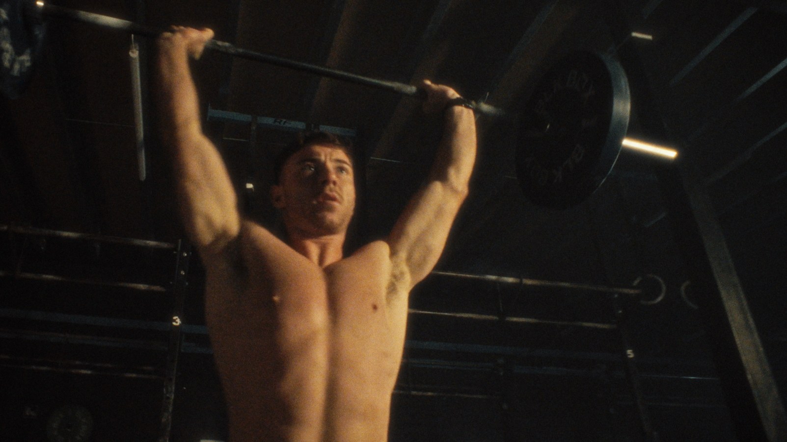 A barbell locked out overhead in the gym.