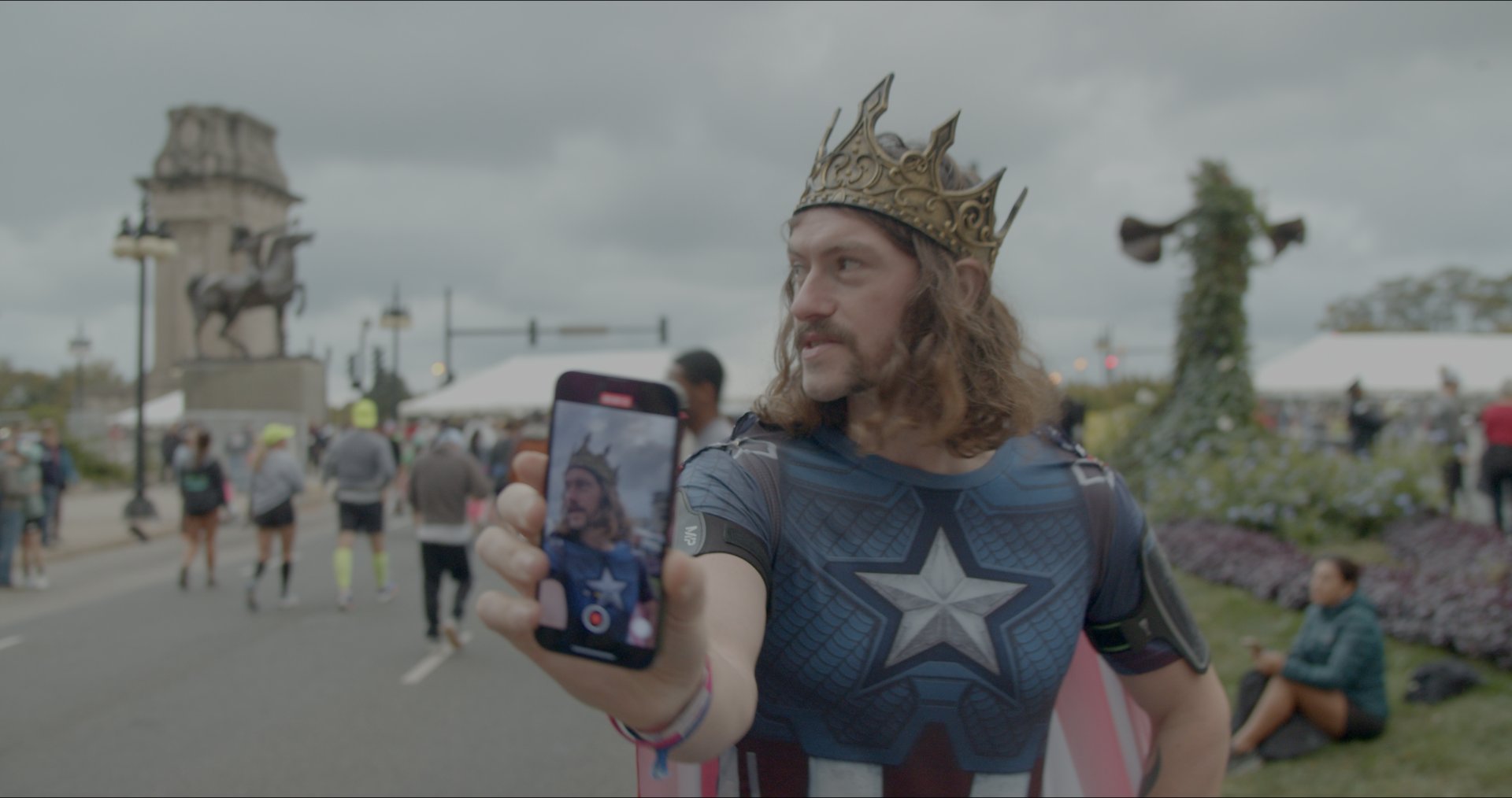 Iain filming himself on his phone, crown on, mid-course.