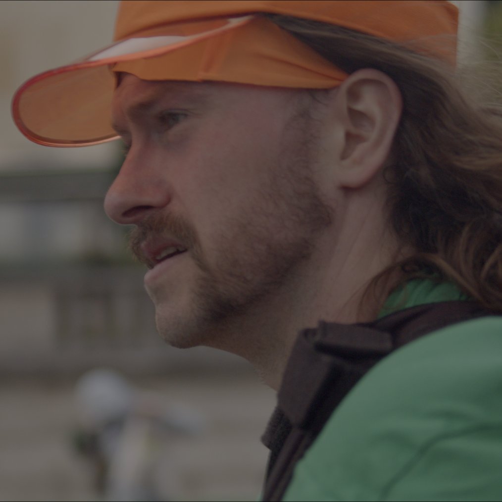 In profile under the orange visor, the Paris course soft behind him.